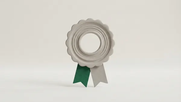 A grey clay rosette seal with a hollow centre and two ribbon tails, one of them green