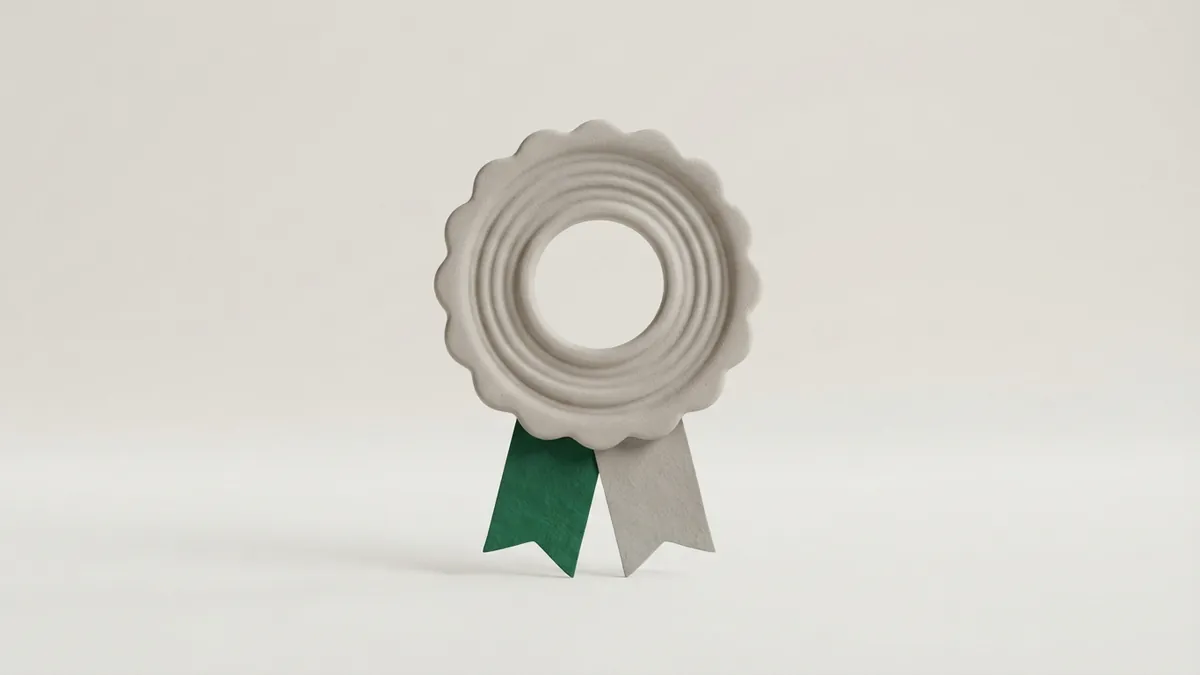 A grey clay rosette seal with a hollow centre and two ribbon tails, one of them green