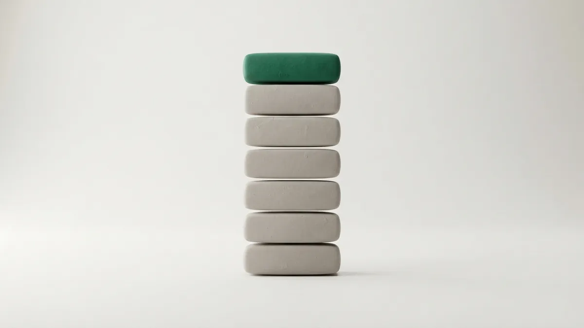 Seven rounded clay tiles stacked in a column, six grey and the top one green